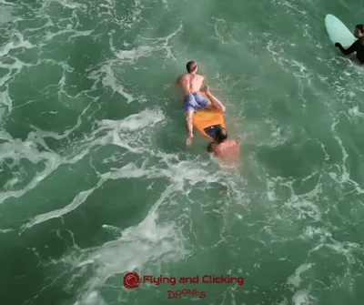 Surfistas ajudam turista a sair do mar na Praia da Barra